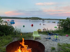 A lakeside setting with a fire pit, outdoor chairs, and boats on the water. - Spacious waterfront Berkshire home family private get-away (Otis)