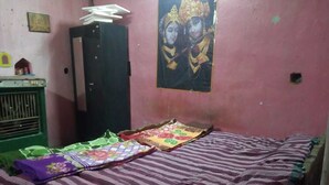 A room with a bed covered by a striped blanket, a green cabinet, and a wall with a framed picture. - Dandak Tribes Homestay and Tourism group! Bastar Homestay! (dantewada)