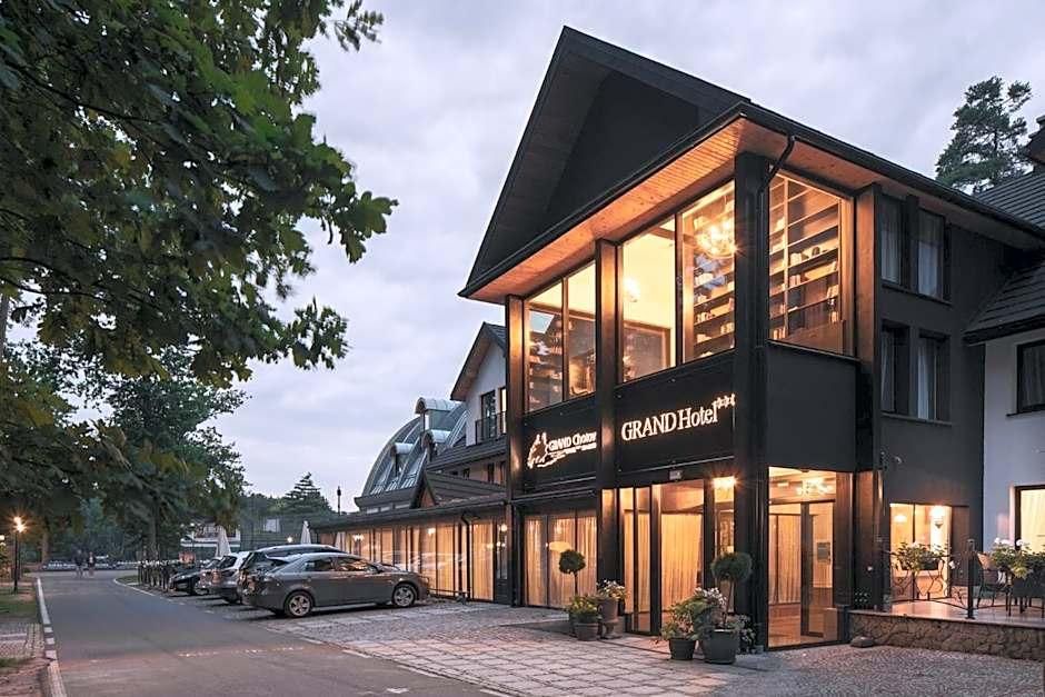 A hotel with a prominent sign, large windows, and a parking area with cars.