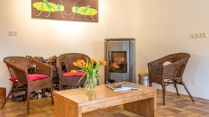 Ein Wohnzimmer mit Korbsesseln, einem Holztisch, einer Vase mit Blumen, einem Kamin und einem Gemälde an der Wand.