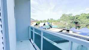 Ein Balkon mit Blick auf ein grünes Gebäude und Bäume.