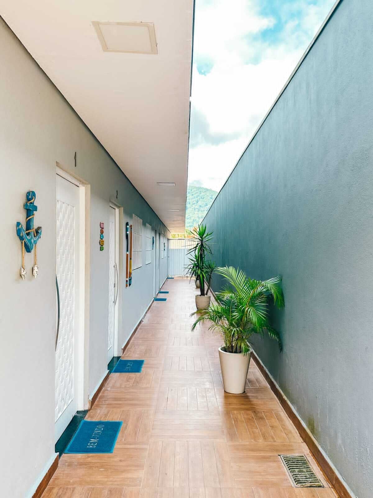A long hallway with doors, potted plants, and a blue mat on the floor.