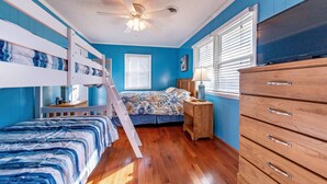 A room with bunk beds, a wooden dresser, a ceiling fan, and a TV. - Landing Pad - Kill Devil Hills, Oceanside, 350 Yards to Beach, YR Flex Stays, 4 BR (Kill Devil Hills)