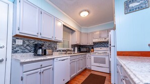 A kitchen with white cabinets, a microwave, a coffee maker, and a dishwasher. - Landing Pad - Kill Devil Hills, Oceanside, 350 Yards to Beach, YR Flex Stays, 4 BR (Kill Devil Hills)