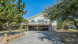 A two-story house with a wooden deck and a covered porch. - Landing Pad - Kill Devil Hills, Oceanside, 350 Yards to Beach, YR Flex Stays, 4 BR (Kill Devil Hills)