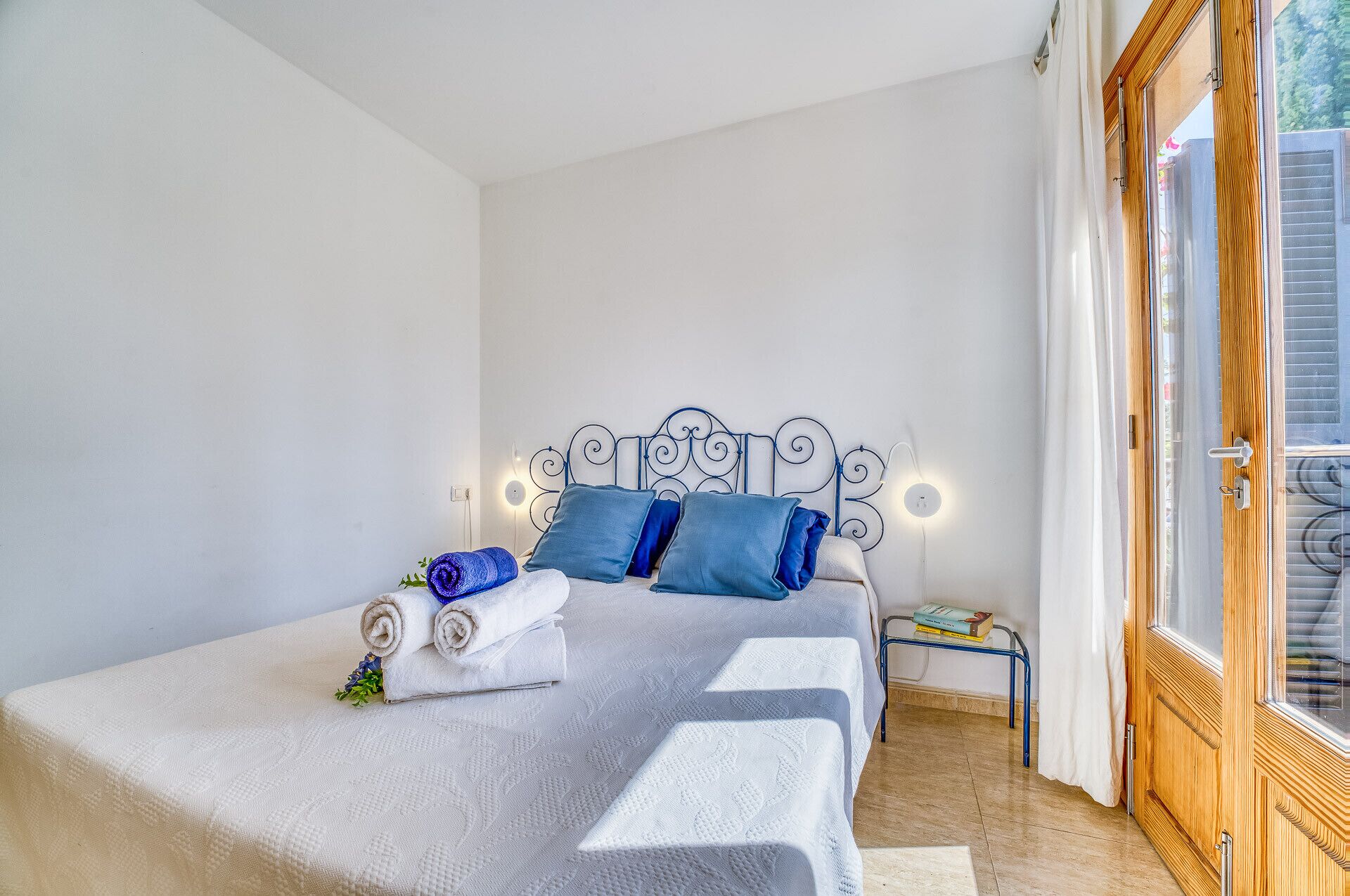Un lit bien fait, avec une couvre-lit à motifs, des oreillers bleus et des serviettes enroulées.