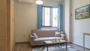 Ein Wohnzimmer mit einer Couch, einem Couchtisch und einem Fenster mit Vorhängen.