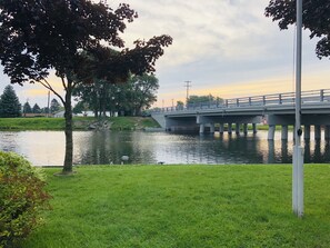 A bridge over a calm river with grassy banks and trees.