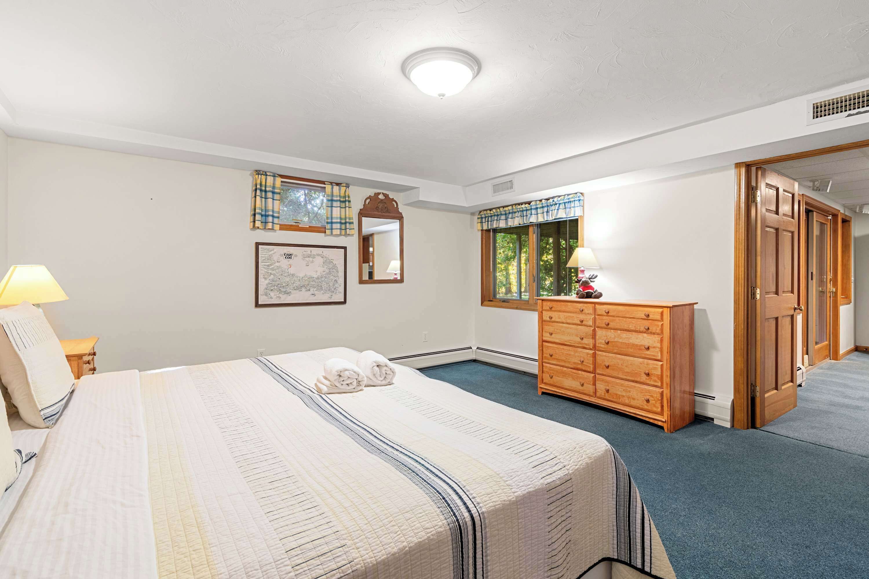 Une chambre d’hôtel avec un grand lit, une commode, un miroir et une fenêtre avec des rideaux.
