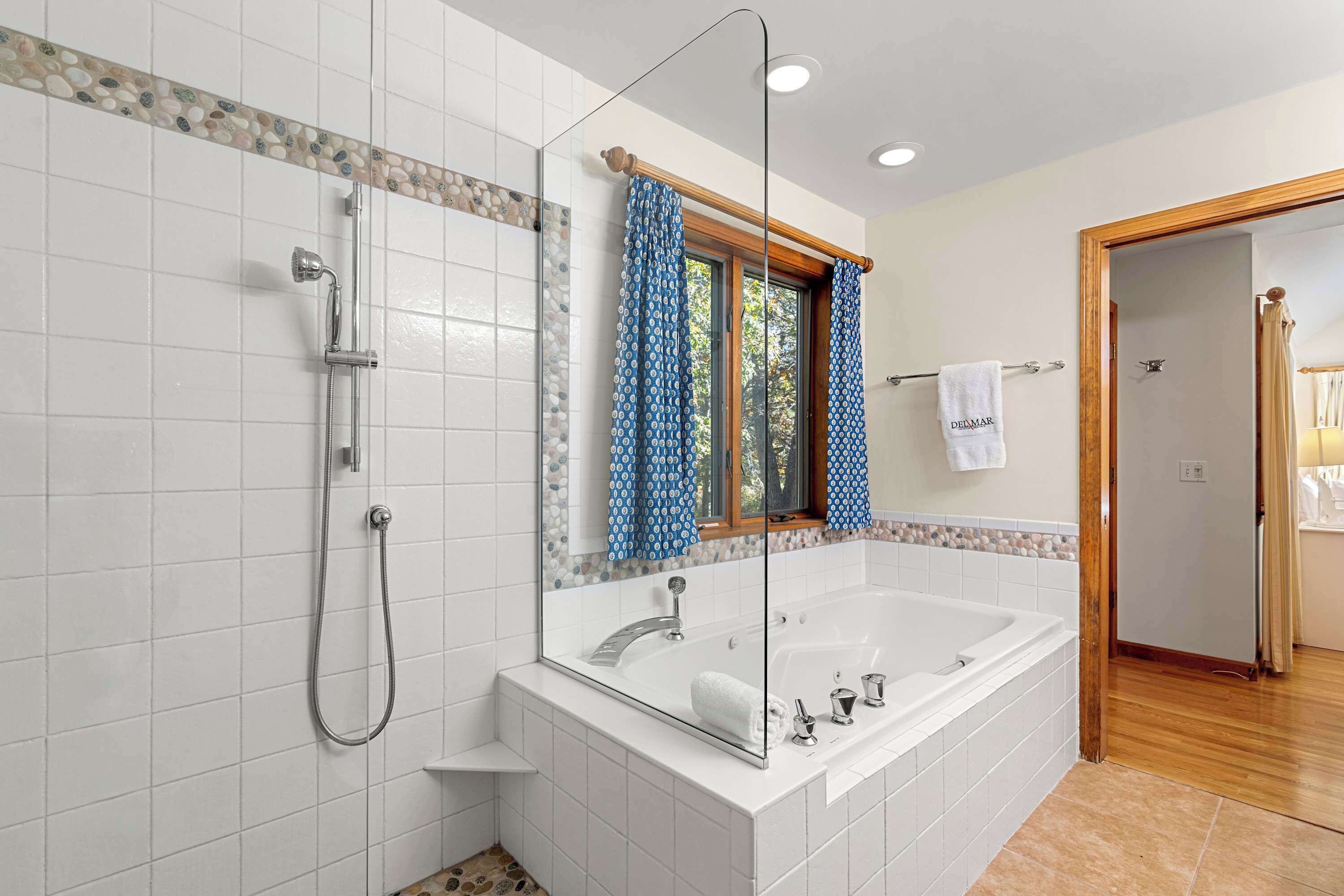 Un baño moderno con una bañera grande, una ducha y un espejo con ventana.