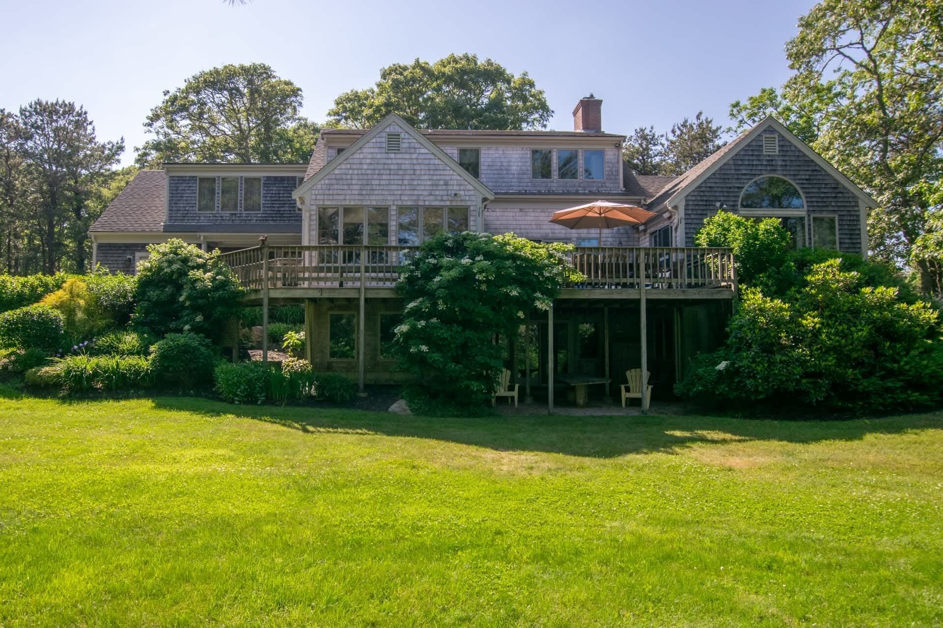 A large house with a covered porch, a deck, and a well-maintained garden.