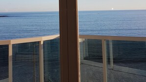 A view from a balcony with a glass door leading to a terrace. The terrace has a tiled floor and a railing. - INCREADIBLE VIEW! UNFORGETABLE PLACE! YOU MUST TRY IT! (Guarapari)
