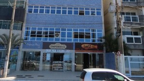 A multi-story building with a curved facade, large windows, and a ground-level storefront. - INCREADIBLE VIEW! UNFORGETABLE PLACE! YOU MUST TRY IT! (Guarapari)