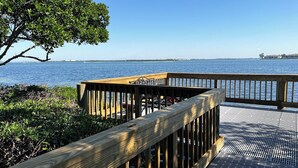 A wooden deck with a railing overlooking a body of water. - Runaway Bay 135 - Beach, Pool, gym and bay (Bradenton Beach)