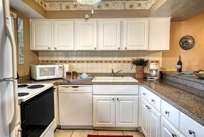 Compact kitchen with a stove, microwave, dishwasher, and sink.