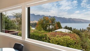Una habitación con un amplio ventanal que da a un paisaje montañoso y una masa de agua.
