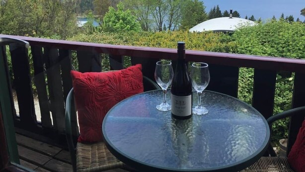 Una mesa de vidrio con una botella y vasos en un balcón con vista a la montaña.