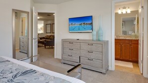 A bedroom with a bed, a dresser, a TV, and a painting of a pool. - Kids Bedrooms | Games | Screened Pool | Near Attractions (Kissimmee)