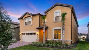 A two-story house with a garage, a well-maintained lawn, and a clear sky. - Kids Bedrooms | Games | Screened Pool | Near Attractions (Kissimmee)