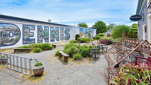 Un patio con un mural que dice 'DENNIS PORT', mobiliario exterior y una valla metálica.