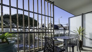 A balcony with a table and chairs, a potted plant, and a view of the street and buildings. - L'Ilôt Bateau apartment very close to the corniche for 2 people (Concarneau)