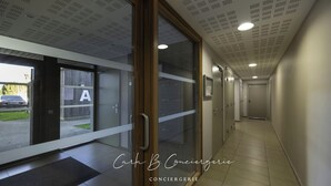 A hallway with glass doors, a reception area, and a parking lot visible through the glass. - L'Ilôt Bateau apartment very close to the corniche for 2 people (Concarneau)