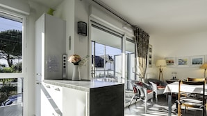 A modern kitchen with a large window, a dining area with wicker chairs, and a table set for two. - L'Ilôt Bateau apartment very close to the corniche for 2 people (Concarneau)