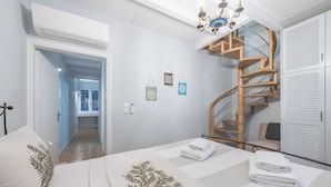 Un dormitorio con una cama, una escalera espiral de madera y vistas al pasillo.