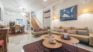 Amplia sala de estar con sofá, mesa de centro y una escalera que conduce a otro nivel.