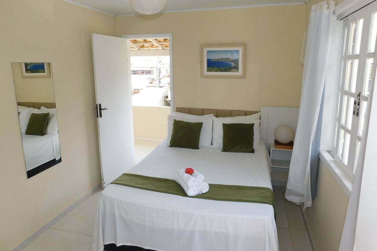 Ein Hotelzimmer mit Bett, einem Vorhangfenster, einer Tür, die nach draußen führt, und einem an der Wand hängenden Bild.