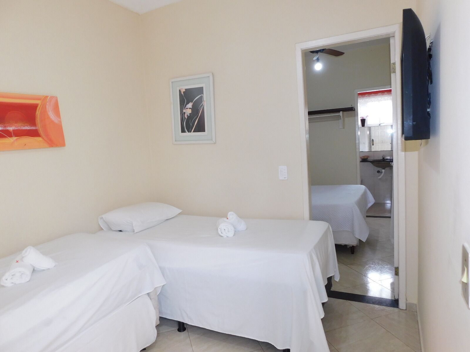 Una habitación de hotel con dos camas, un cuadro y un televisor.
