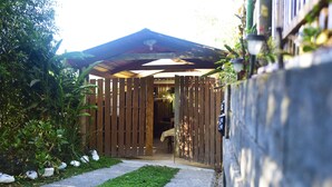 A wooden structure with a sloped roof, a concrete pathway leading to it, and a wall with a light fixture. - Santa Ana City Views Breathtaking Chalet (Santa Ana)