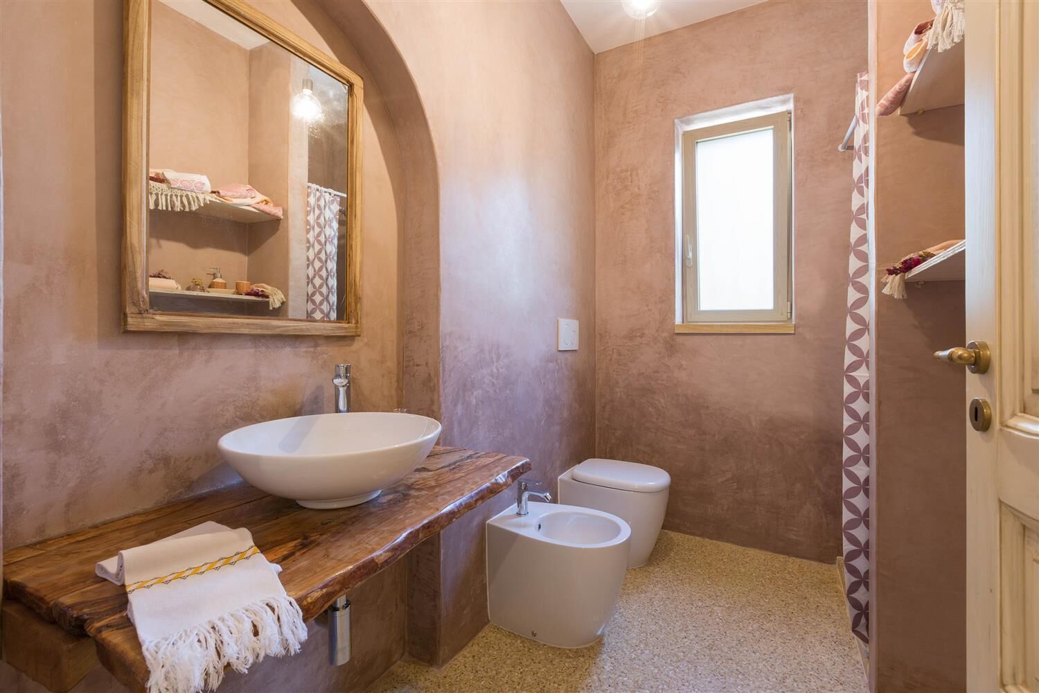 A bathroom with a large oval sink, a toilet, and a mirror.
