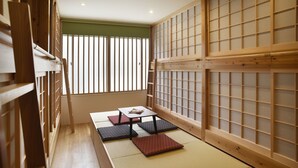 A traditional Japanese room with tatami flooring, a low table with cushions, and shoji screens. - Ten Apartment Hotel (Fukuoka)