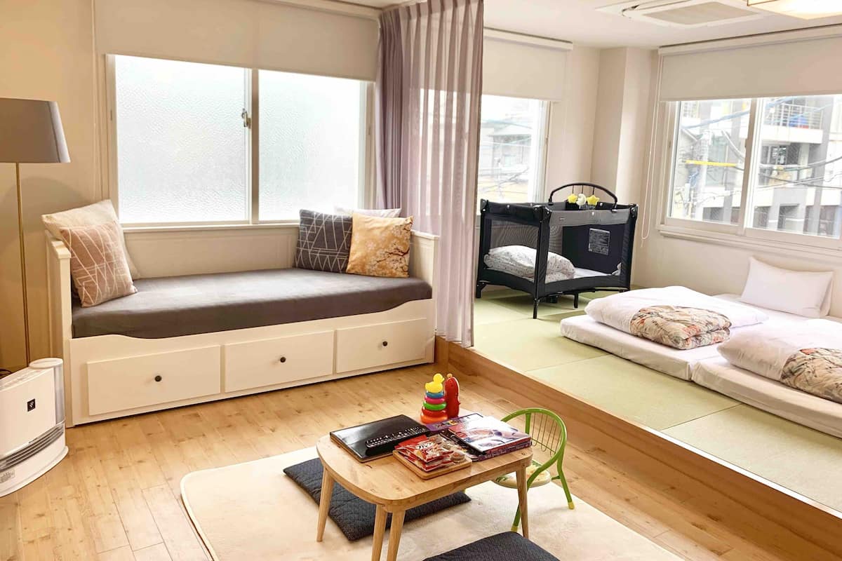 Ein kindgerechtes Zimmer mit eingebauter Bank, einem kleinen Tisch mit Spielzeug und Büchern, einem Etagenbett und großen Fenstern.