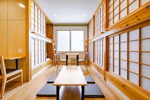 Una habitación japonesa tradicional con suelo de tatami, una mesa baja y puertas correderas.