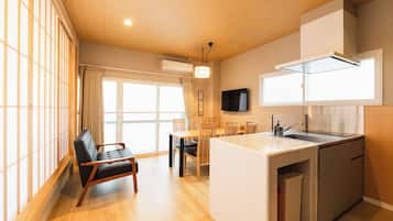 A compact kitchen with a dining area, a built-in refrigerator, and a flat-screen TV mounted on the wall.