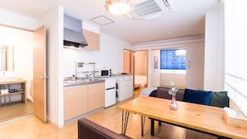 A compact kitchen with modern appliances, a dining area with a wooden table, and a view of the outside through a window.