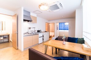 Eine kompakte Küche mit modernen Geräten, ein Essbereich mit Holztisch und Blick ins Freie durch ein Fenster.