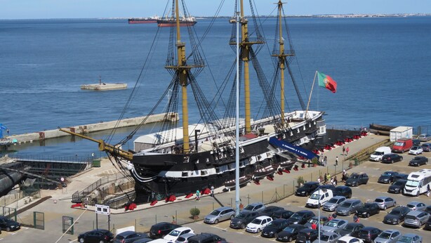 A large sailing ship docked at a port with a parking lot in the foreground. - TEJO HOUSE RIVER Lisbon (Cacilhas) (Almada)