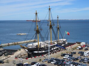 A large sailing ship docked at a port with a parking lot in the foreground. - TEJO HOUSE RIVER Lisbon (Cacilhas) (Almada)
