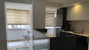 A modern kitchen with black cabinets, a stainless steel sink, and a glass dining table. - TEJO HOUSE RIVER Lisbon (Cacilhas) (Almada)