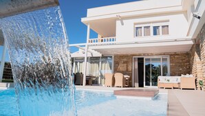 Ein modernes, zweistöckiges Haus mit Pool und Wasserfall.