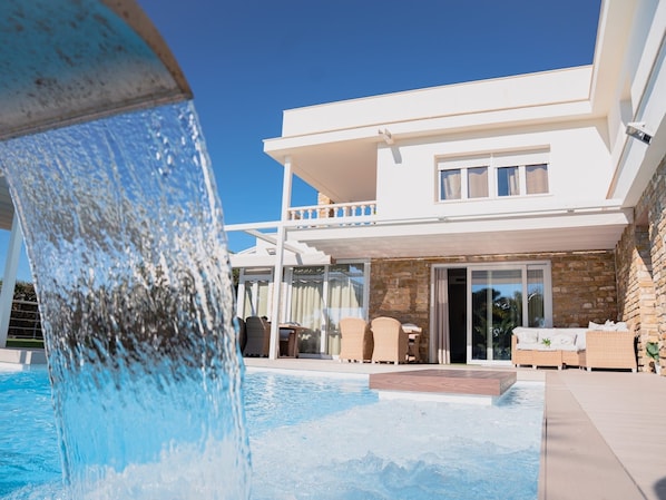 Una casa moderna de dos pisos con piscina y una cascada.
