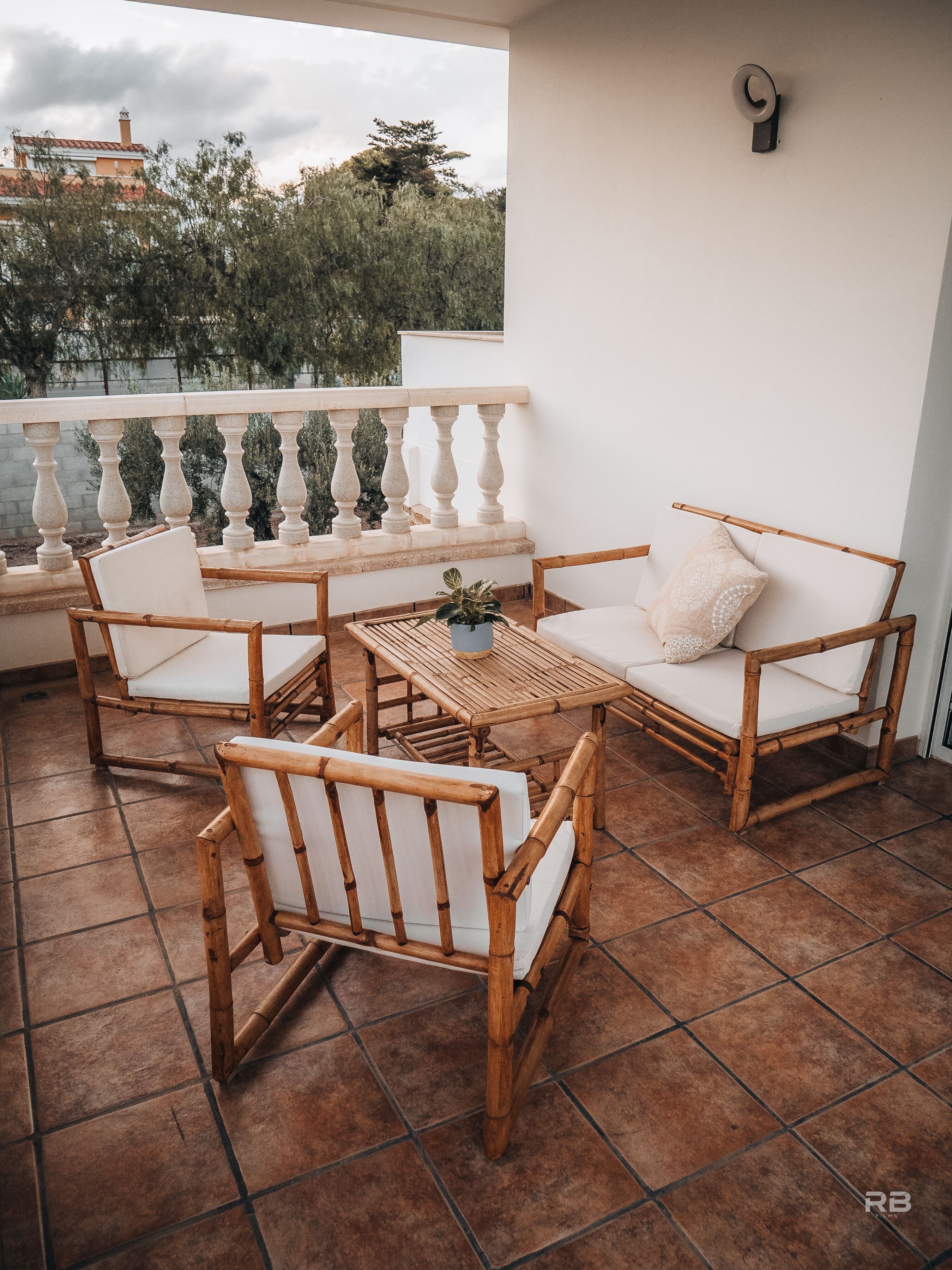Un balcon avec une balustrade blanche, une table et quatre chaises dotées de coussins blancs.