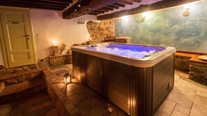 A hot tub in a stone-walled room with a rustic ambiance, stone flooring, and a wooden ceiling. - Stone Rustico with Jacuzzi, Infrared Sauna Escluiva   (Boveglio)