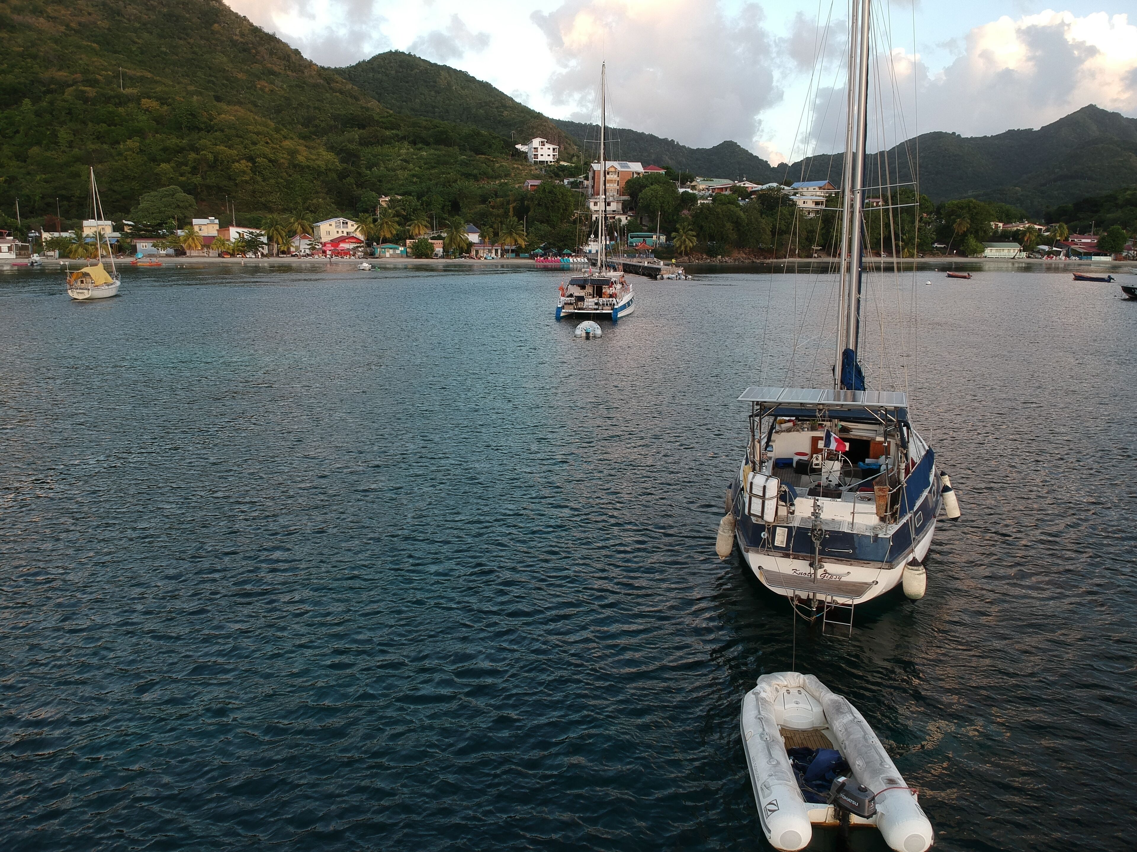 A marina with boats, a sailboat, and a small inflatable boat.