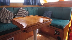 Ein kompakter, gut beleuchteter Innenraum mit Holztisch und grün gepolsterten Sitzgelegenheiten.