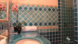 A bathroom with a blue and white tiled wall, a sink, a mirror, and a potted plant.