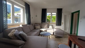A modern living room with a sectional sofa, a round coffee table, and a wooden dining table. - The Steinbock Lodge (Zell am See)